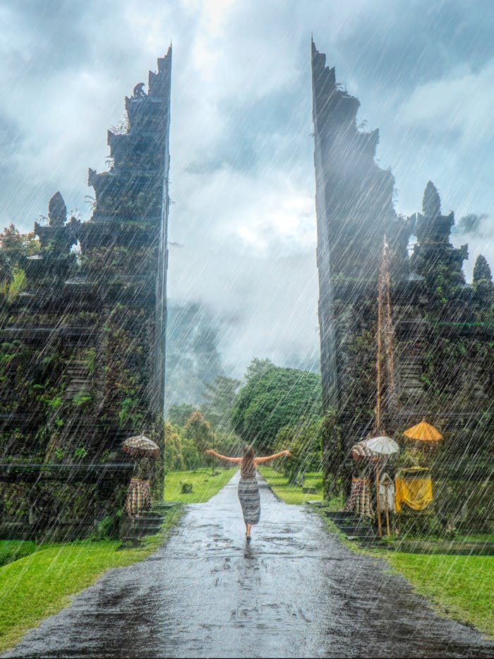 cta-01 Woman in vibrant rain at iconic Handara Gate, Bali. A magical travel moment.