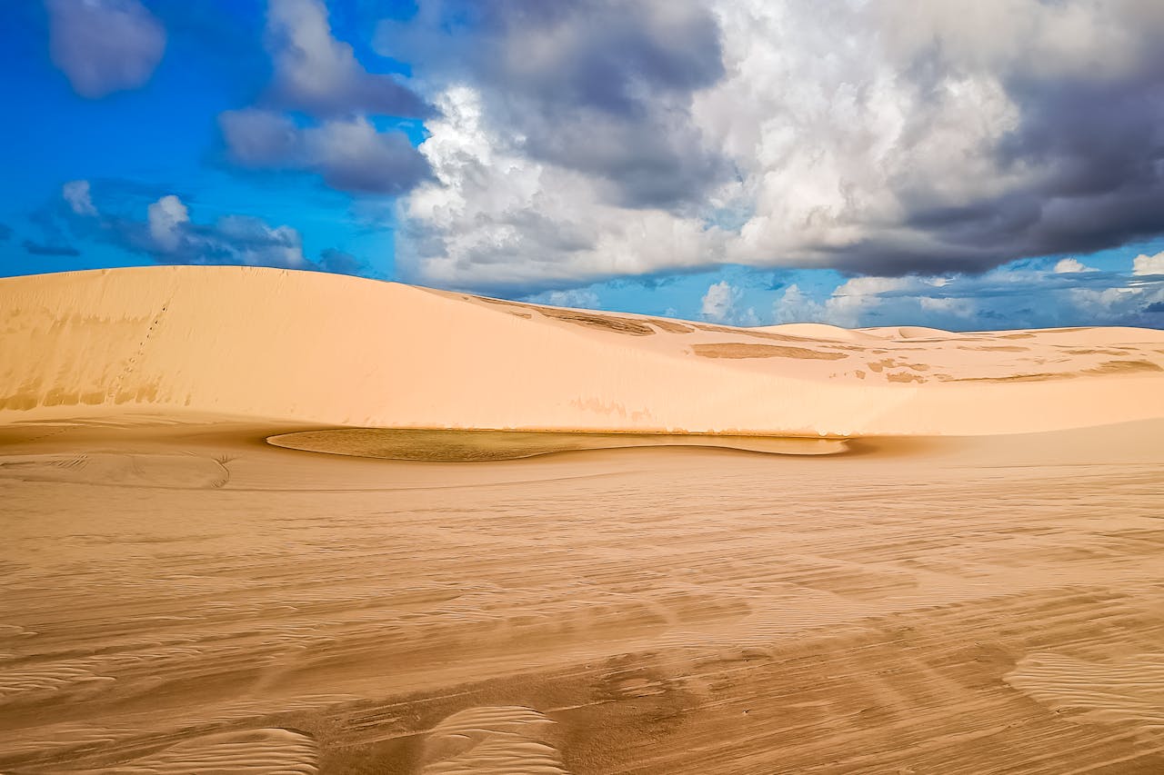 hero-gallery-04 Explore the vast sand dunes of Maranhão, Brazil, set against a backdrop of dramatic, cloudy skies.