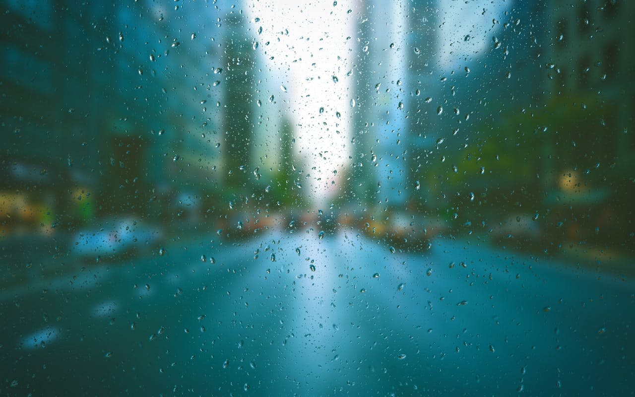 programs-03 Blurred city scene through raindrop-covered window, creating a tranquil urban mood.