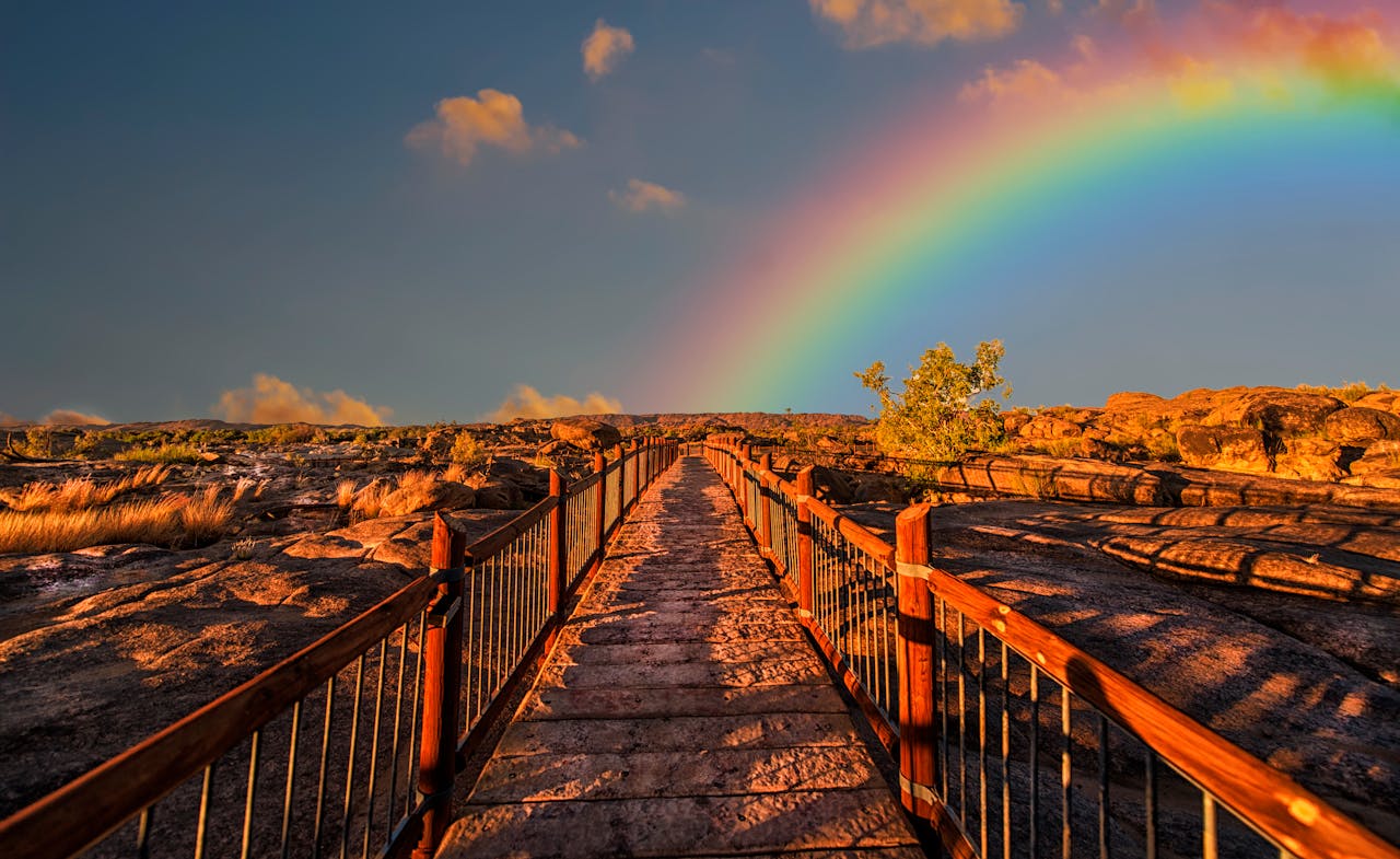 programs-02 A scenic walkway with a rainbow arching across a vivid sky, perfect for outdoor photography.